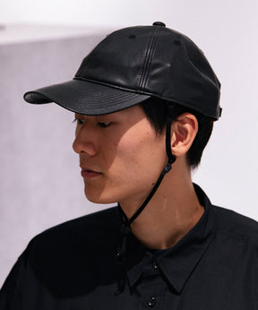 黒いフェイクレザーの帽子を被った男性の横顔です